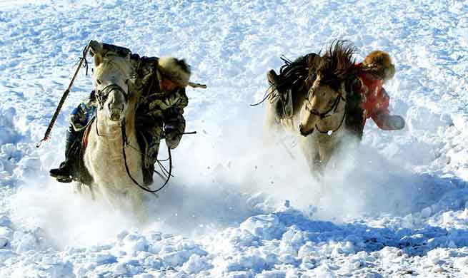 Herdsmen tame horses on snow-covered pasture in N China